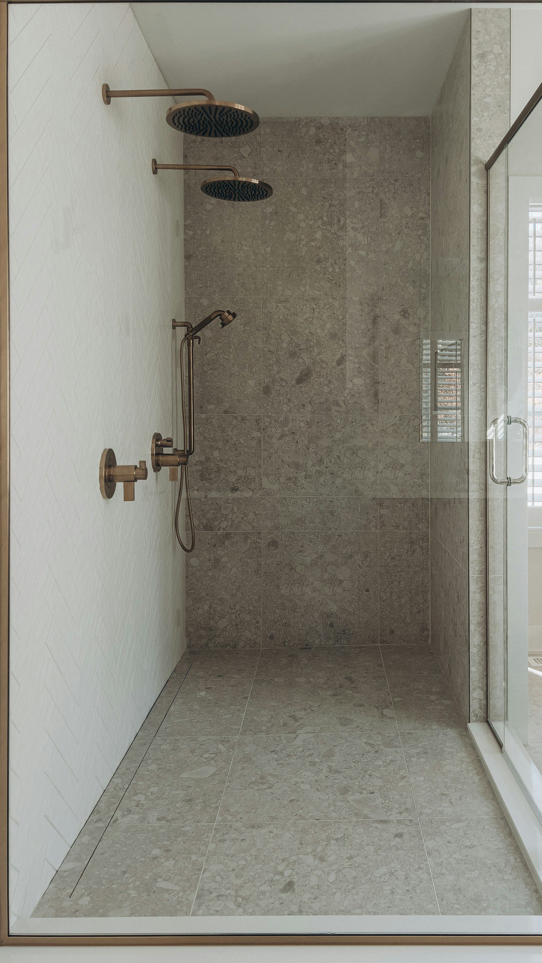 Walk-in shower with gray tile beside a window